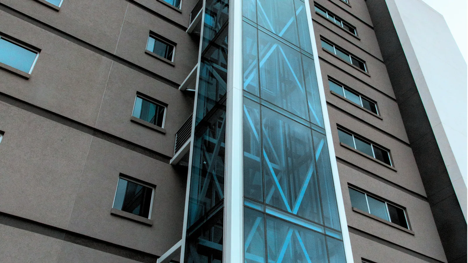 External glass elevator installed against a multi-storey building