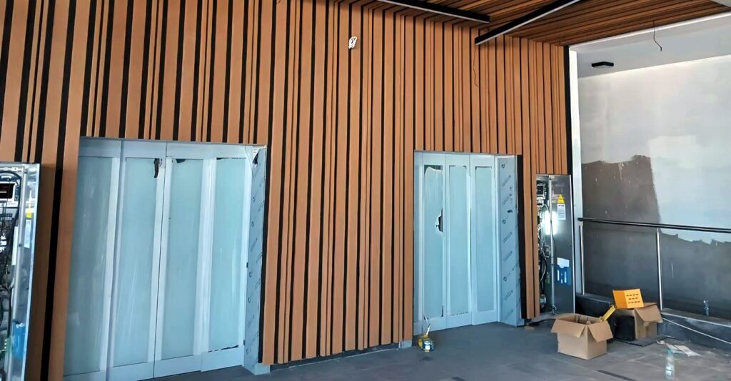Twin passenger elevator entrances set within timber wall cladding during installation.