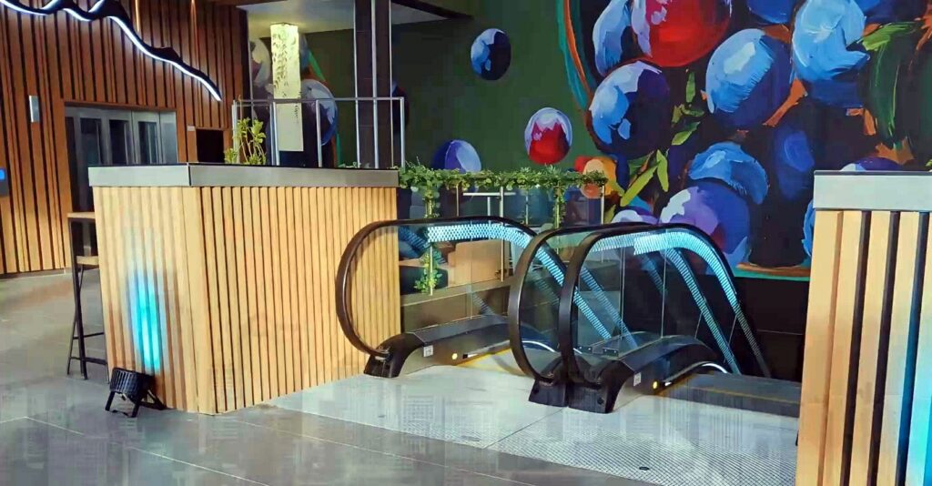 Completed escalator entrance integrated with timber and mural finishes.