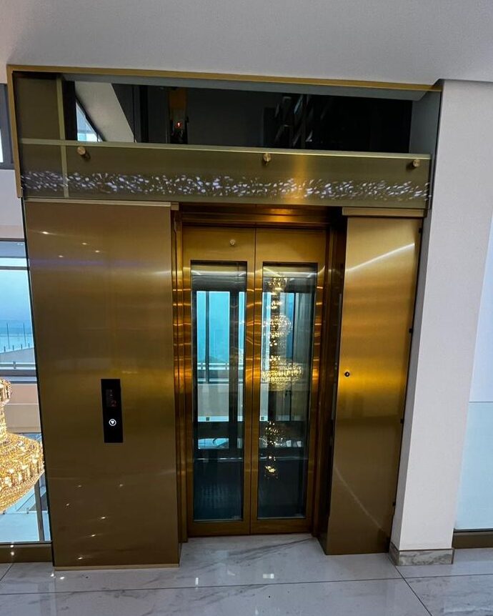 Gold-toned passenger-elevator entrance with glass door panels.