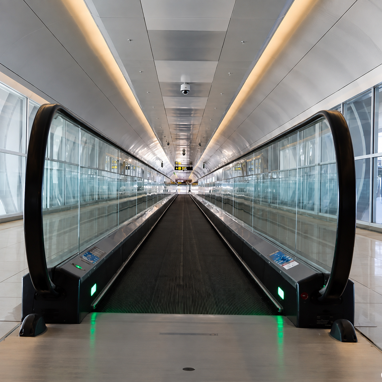 Horizontal moving walk with glass sides along an enclosed corridor.
